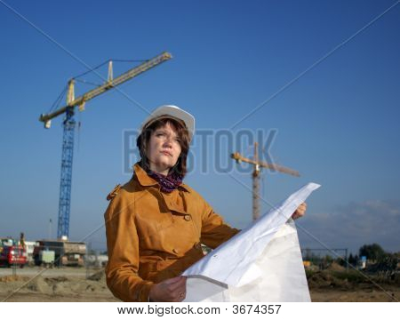 Giovane architetto guardando Blueprint davanti al cantiere contro il cielo blu