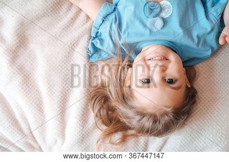 Close Up Top View Toddler Girl Lying In Bed. Woke Up Looks At Camera Feels Happy. Comfy Mattress, Dr