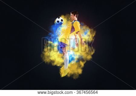Soccer Player Jumping With Ball In Smoke. Sportsman In Yellow And Blue Uniform In Action. Soccer Gam