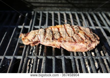 Steak on a Barbecue Grill. Steak being grilled for dinner or lunch. Red meat being prepared for a meal. BBQ Grilled Steak. Meat being cooked for dinner. 
