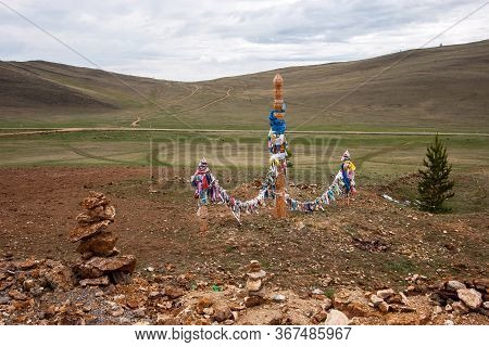 Sacred Pillars With Ribbons For Shamanistic Rites On A Background Of Hills. Shamanistic Rite Of Bury