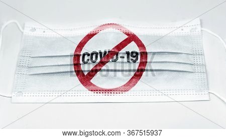 Surgical Mask With The Prohibition Red Sign To Coronavius Covid-19 Printed. Pandemic Covid-19 And Pr