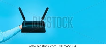 Black Wifi Router On Hand Over Blue Background