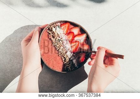 Pink Smoothie From Banana And Strawberries With Pieces Of Strawberries, Granola And Coconut Shreds O