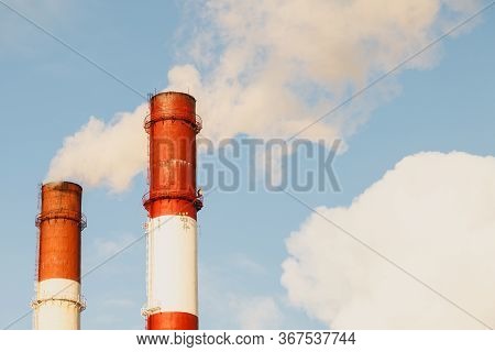 Two Pipes And Smoke. Close-up From Below Of Smoke Coming Out Of Pipes Against Blue Sky. Two Chimneys