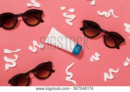 Sun Protection Composition With Tube Of Cream, Sunglasses And Cream Strokes On Pink Background Top V