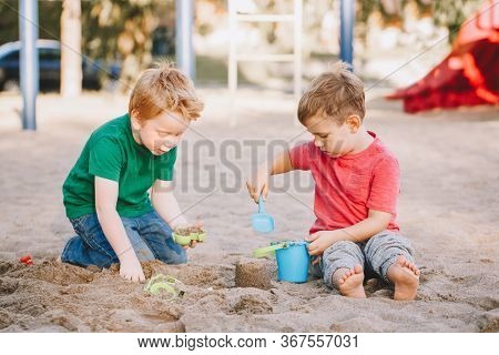Two Caucasian Children Sitting In Sandbox Playing With Beach Toys. Little Boys Friends Having Fun To