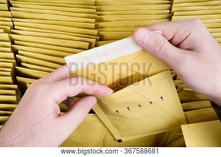 Self Sealed Mailing Envelope Quality Inspection. Male Hands Open One Yellow Bubble Mailer Out Of A B