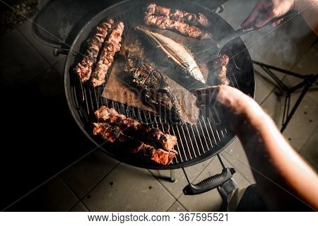 Top View On Hands Of Chef Who Straightens Grilled Meat And Fish