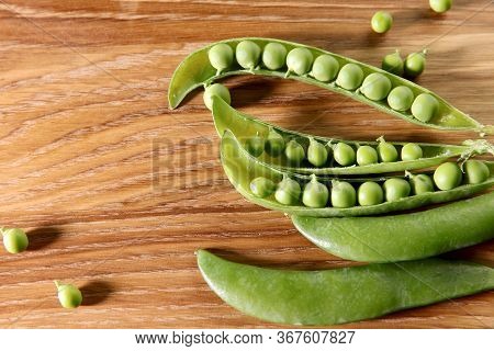 Food Background. Close-up Of Opened Green Pea Pods On A Wooden Table. Texture Of Green Pea Pod. Top 