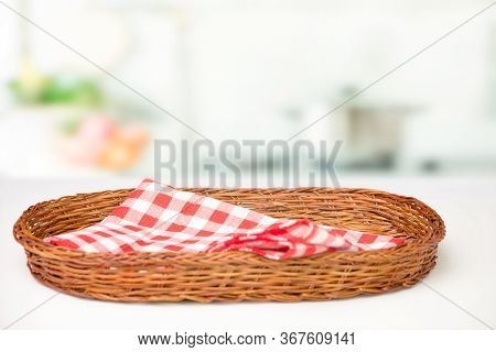 Wicker Oval Basket With A Red Checkered Napkin On The Table