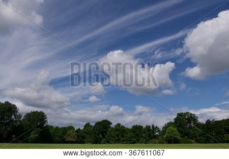 Unusual Cloud Formation In Blue Sky Above Trees And Green Field