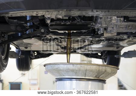 Old Oil Is Drained From The Car Engine. Car Maintenance. Car Engine Bottom View. Changing The Engine