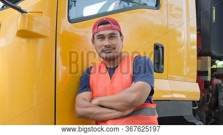 An Asian Man Was Smiling Happily Beside The Yellow Truck. He Has A Career As A Transport Driver. The