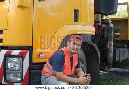 An Asian Man Was Smiling Happily At The Yellow Truck. He Has A Career As A Transport Driver. The Tra