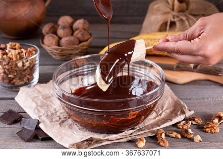 Woman Hands Pour Frozen Banana With Chocolate. Frozen Chocolate Covered Bananas On A Stick