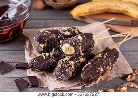 Frozen Banana Covered With Chocolate And Nuts On Wooden Rustic Table