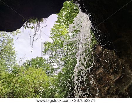 Waterfall In A Forest Mountain Gorge. Yellow Tale. Green Forest.