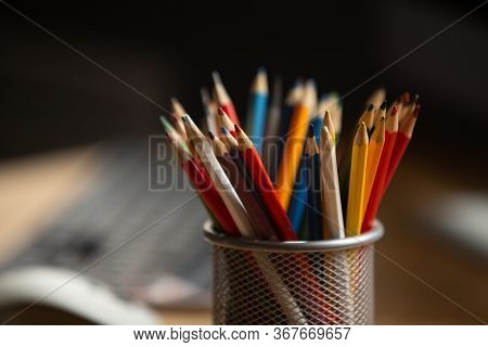 Office Workplace. Focus On Multi-color Pencils In Foreground At Wooden Table With Laptop Computer On