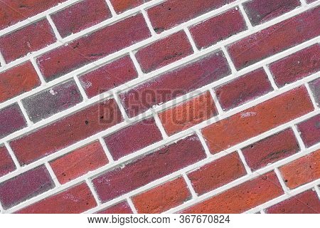 Photo Of A Sloping Dark Red Brick Wall. Dark Red Brick Wall For Background Or Texture. Old Red Brick