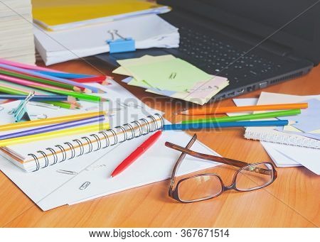 Glasses On The Background Of Colored Pencils And Paper. The Clutter On The Desktop.