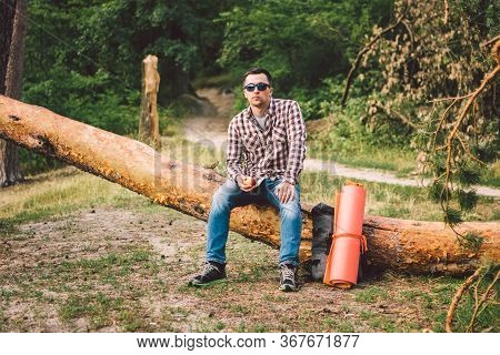 Man Eating An Apple On Hiking Trip In Forest. Hiker Taking Break While Trekking In Wilderness. Male 