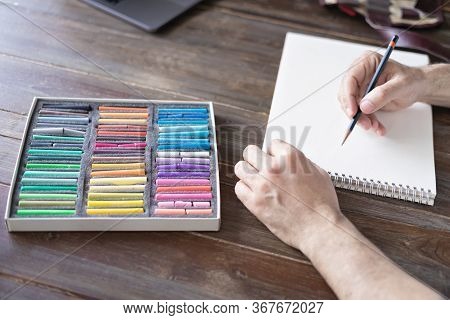 Person Painting With A Pastel Crayon Chalk On A White Sheet Of Paper With Pallette Of Pastel Chalks 