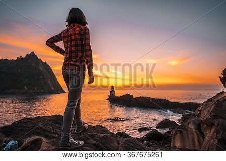 A Young Woman Looking At The Beautiful Lighthouse At Pasajes San Juan, Near San Sebastian, Gipuzkoa.