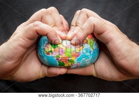 Man Squeezing A Globe, Symbolic Of Flat Earth, Concept Of Conspiracy Theory, Closeup Fingers And Glo