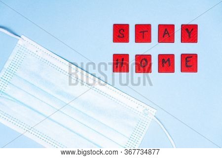 Medical Protective Mask On Blue Background And Lettering Inscription Stay Home. Disposable Face Mask
