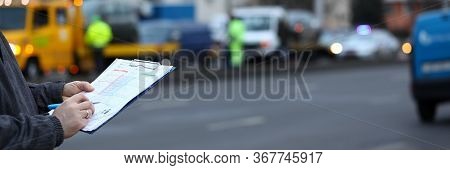 Filling Out Accident Statement At Scene Accident. Man Fills Document Standing On Road. Driver Draws 