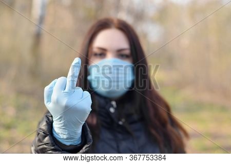 Portrait Of Young Brunette Woman In Blue Protective Mask And Rubber Gloves Shows Fuck You Gesture Ou