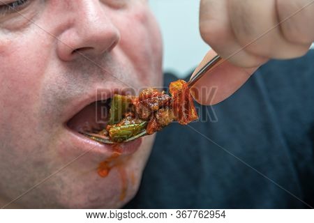A Hungry And Fat Fat Man Eagerly Eats Roasted Meat With Spices, Fat From His Mouth Flows Through His