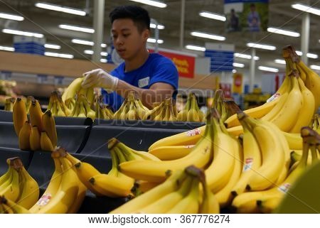 Coquitlam, BC, Canada - September 11, 2017 :  Blur motion of clerk stocking banana on display rack inside superstore produce department