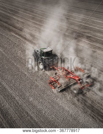 Aerial View Of A Clean Field In Which The Tractor Makes Vertical Tillage. Red Tillage Equipment And 