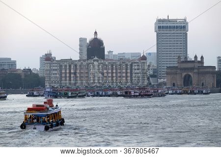 MUMBAI, INDIA - FEBRUARY 15, 2020: Taj Mahal hotel, Gateway of India and tourist boats in water of Arabian Sea in Mumbai, India