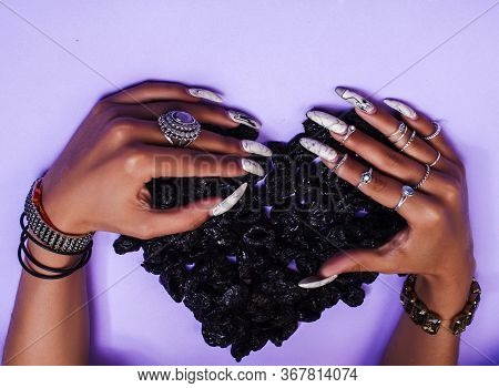 Woman Hands With Long Nails Manicure Holding Dry Fruits In Shape Of Heart On Purple Background