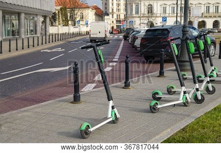 Electric Scooter Parked On The Road. Modern Eco Electric City Scooters For Rent Outdoors On The Side