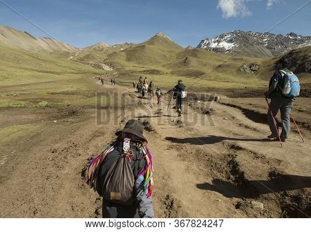 Cusipata, Peru - June 08, 2017: Peruvian Andean Man And Tourists Walking Up The Hill In The Way To V