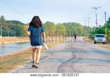 Sportive Woman Take Off Protective Mask While Jogging For Easier Breathing On Road Beside Irrigation