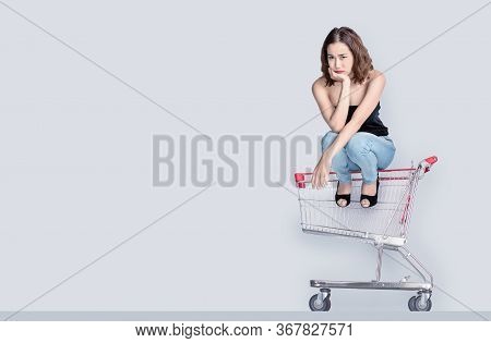 Worry Face Of Asian Woman Waiting To Shopping With Sitting On Empty Shopping Cart And Blank Backgrou
