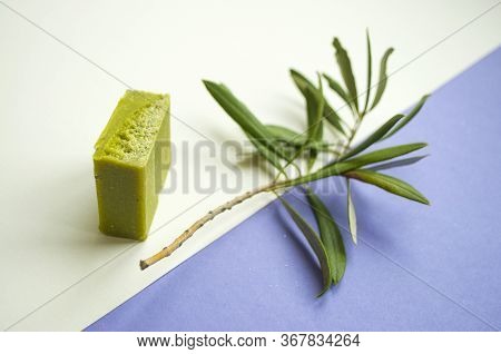 Flat Lay Of An Olive Branch, Handmade Olive Soap Bars On Purple And White Background.
