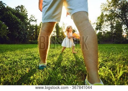 Father Plays With His Daughter On A Tarve Ball In A Park At Sunset.