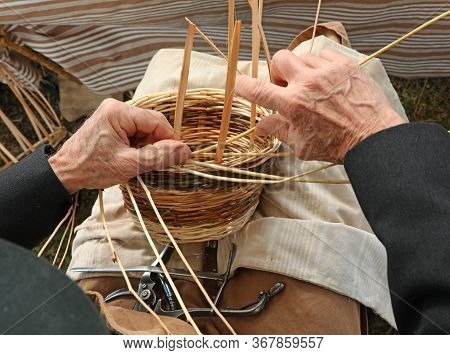 Senior With Hands With Arthrosis While Weaving Wicker Branches To Create A Handmade Basket For Sale 