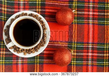 Top View, A Cup Of Black Coffee With Coffee Beans And Two Red Christmas Balls On Red Heckered Backgr