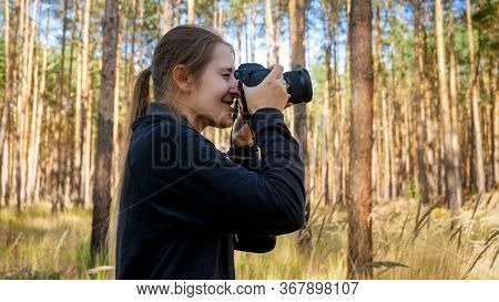 Portrait Of Smiling Wild Nature Female Photographer Making Photograph On Digital Camera At Forest