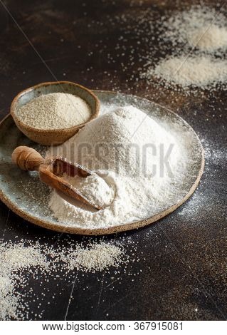Raw Fonio Flour And Seeds On A Plate With A Spoon On Dark Background Close Up. Alternative Flour