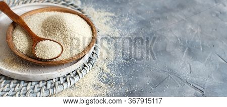 Raw Uncooked Fonio Seeds With A Spoon On A Plate On Grey Background Close Up With Copy Space