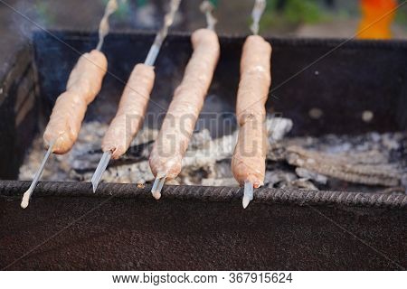 Close Up Of Toasted Sausages On Skewers. Succulent Kupaty Roasting On Chargrill. Concept Of Picnic O