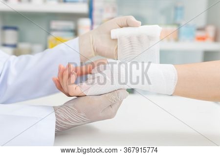 Close-up Hand Wear Medical Gloves  Of Doctor Hand Tying Bandage On The Hand Of Patient In Clinic, Os